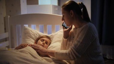 Küçük hasta çocuk annesinin yanında uzanmış telefonla doktorla konuşuyor. Çocuk hastalığı, hastalık ve ebeveyn bakımı kavramı