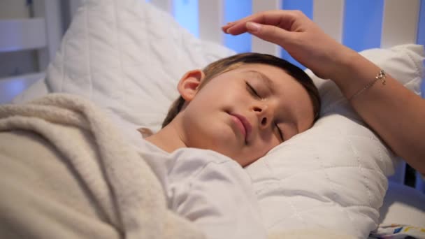 Zorgzame en liefhebbende moeder strelen en kussen van haar slapende zoon in voorhoofd.Concept van ouderschap en familie geluk — Stockvideo