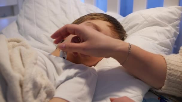 Mutter schaut auf Thermometer und überprüft Körpertemperatur ihres kranken kleinen Jungen. Konzept der Kinderkrankheit und der elterlichen Betreuung — Stockvideo