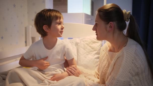 Young loving mother stroking and hugging her little sick son lying in bed at night. Concept of children illness, disease and parent care — Stock Video