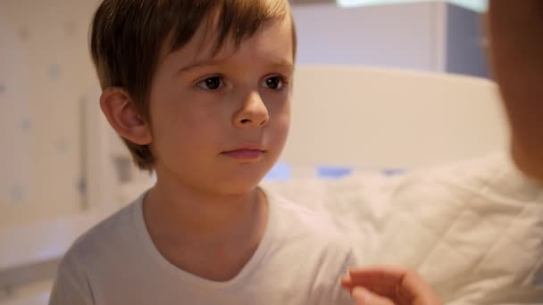Маленький мальчик показывает скорбящее горло своей матери. Концепция детских болезней, болезней и ухода за родителями — стоковое видео