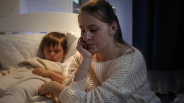 Ung ledsen kvinna orolig för sin lilla sjuka son sova i sängen. Begreppet ensamstående mor, familjeproblem och depression hos modern — Stockvideo