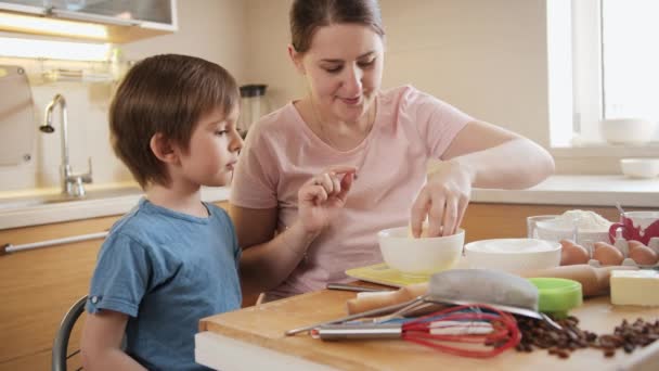 Kleine jongen met jonge moeder die ingrediënten controleert en weegt op digitale weegschalen. Kinderen koken met ouders, kleine chef-kok, familie hebben tijd samen, huishoudelijke keuken. — Stockvideo