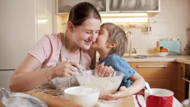 小さな息子にビスケットやケーキの生地を混ぜることを教える若い母親。両親、小さなシェフ、家族と一緒に時間を過ごす子供たち、家庭用キッチン. — ストック動画