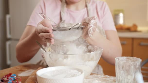 Young woman in apron sifting flour with sieve on kitchen at home. — Stock Video