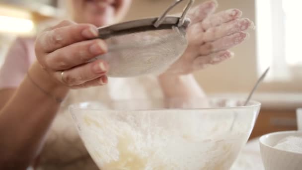 Slow motion of young woman making dough and sifting flour with metal sieve. — Stock Video