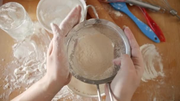 Top view of young woman shaking sieve for sifting flour while making tough — стоковое видео