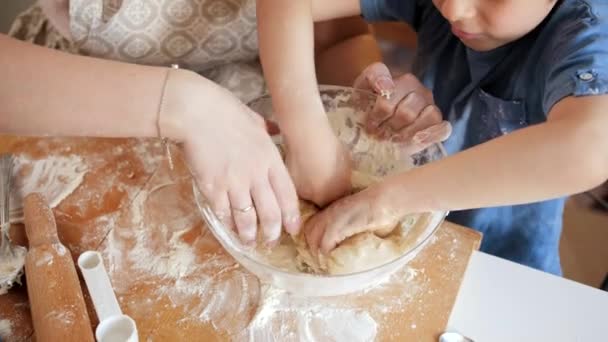 Κάτοψη της μητέρας και του μικρού γιου ανακατεύοντας ζύμη για μπισκότα σε γυάλινο μπολ. Παιδιά μαγείρεμα με τους γονείς, λίγο σεφ, οικογένεια έχοντας χρόνο μαζί, οικιακή κουζίνα. — Αρχείο Βίντεο