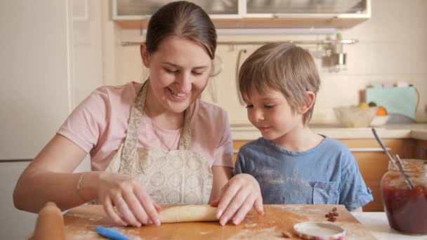 Joven madre enseñando a su pequeño hijo hornear dulce rollo con relleno de mermelada. Niños cocinando con padres, pequeño chef, familia pasando tiempo juntos, cocina doméstica. — Vídeos de Stock