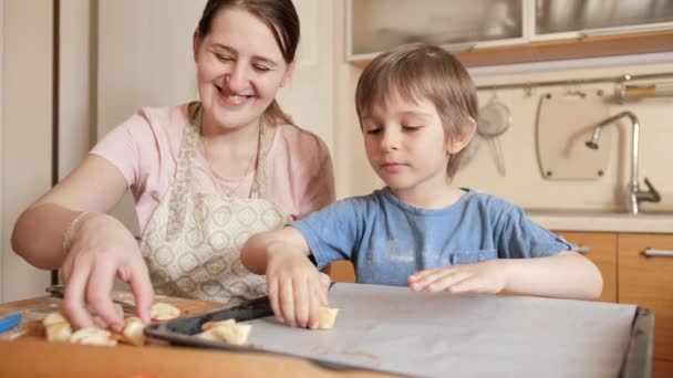 Glimlachende jongen met moeder die koekjes maakt en op bakplaat zet. Kinderen koken met ouders, kleine chef-kok, familie hebben tijd samen, huishoudelijke keuken. — Stockvideo