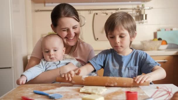 Šťastná rodina s dětmi balí těsto na sušenky nebo koláč v kuchyni. Děti vaří s rodiči, malý šéfkuchař, rodina tráví čas spolu, domácí kuchyně. — Stock video