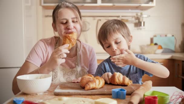 Lindo niño con madre disfrutando comiendo croissants caseros. Niños cocinando con padres, pequeño chef, familia pasando tiempo juntos, cocina doméstica. — Vídeo de stock