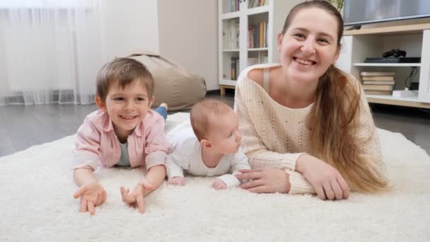 거실 의부드러운 카펫에 누워 있는 아기와 큰 아들 과 함께 미소짓는 어머니는 행복하다. 부모, 자녀 의행 복 및 가족 관계 — 비디오