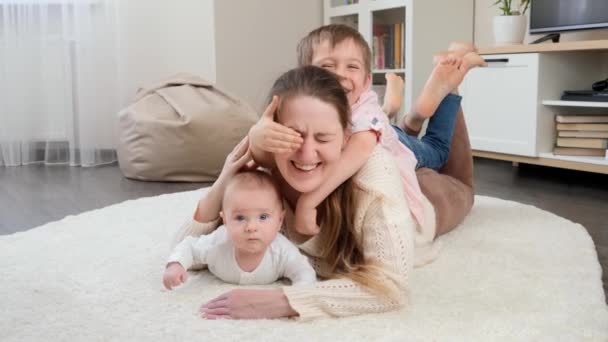거실의 카펫 위에서 쉬고 있는 자녀들 과 함께 행복하게 미소짓고 웃는 가족. 부모, 자녀 의행 복 및 가족 관계 — 비디오