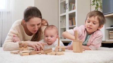 Sevimli erkek bebek ailesiyle birlikte halıda yatıyor ve oyuncak tahta bloklarla oynuyor. Ebeveynlik, çocuklar mutluluk ve aile ilişkisi