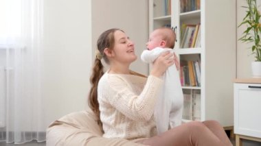 Sırıtan anne, kucağında küçük oğluyla armut çuvalına oturmuş gülümsüyor. Ebeveynlik, çocuklar mutluluk ve aile ilişkisi