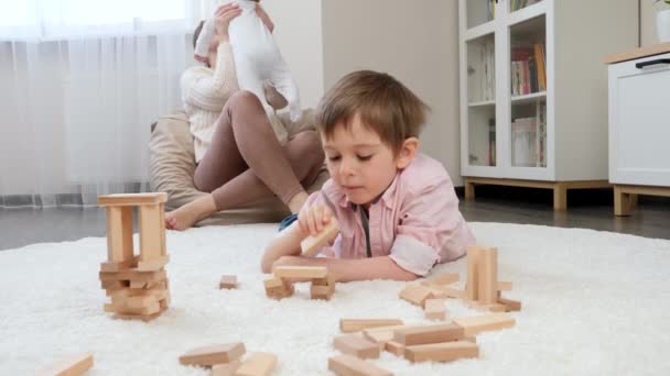 Kleiner Junge spielt auf Teppich neben Mutter mit kleinem Bruder. Elternschaft, Kinderglück und Familienbeziehung — Stockvideo