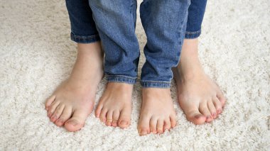 Yumuşak halıda duran ve ayak parmaklarını hareket ettiren kadın ve çocuk ayaklarının yakınlaşması