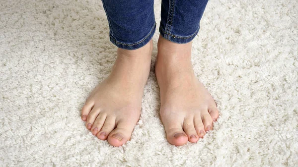 Close-up van barefoot vrouw in jeans staande op zacht wit tapijt en bewegende tenen — Stockfoto