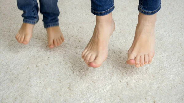 Close-up de mãe e criança pés pulando no tapete macio — Fotografia de Stock