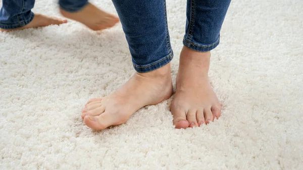 Närbild av barfota mor väntar på sin son springer runt henne på vit matta — Stockfoto