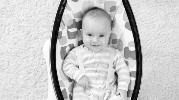 Black and white portrait of smiling little boy lying in crib and smiling — Stock Photo, Image