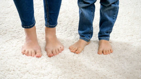 Primer plano de divertida madre descalza con su hijo bailando sobre una suave alfombra blanca —  Fotos de Stock