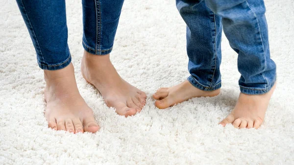 Closeup of childs feet dancing with mothers feet on white soft carpet — Stock Photo, Image