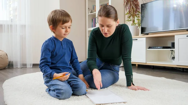 Madre arrabbiata che urla contro il figlio che ha sbagliato a fare i compiti. Concetto di educazione domestica, sviluppo dei figli e problemi genitoriali. — Foto Stock