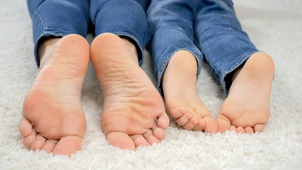 CLoseup de padres e hijos moviéndose en el suelo en casa y moviendo los pies descalzos. Familia divirtiéndose y jugando juntos — Foto de Stock