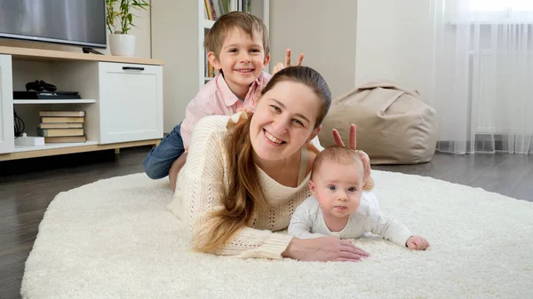 Αστεία οικογένεια δείχνει v σημάδι ή κάνοντας κέρατα στη φωτογραφία στο σαλόνι. Γονείς, παιδιά, ευτυχία και οικογενειακή σχέση — Φωτογραφία Αρχείου