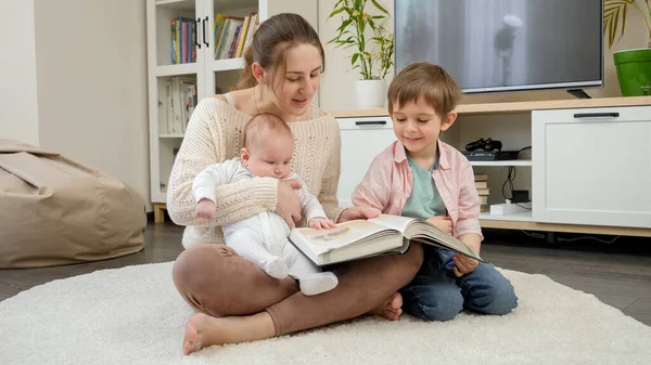 Szczęśliwa rodzina z dziećmi siedzącymi na podłodze w salonie i czytającymi bajki. Rodzicielstwo, szczęście dzieci i relacje rodzinne — Zdjęcie stockowe