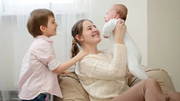 Uśmiechnięty starszy chłopiec bawiący się z młodszym bratem w salonie. Rodzicielstwo, szczęście dzieci i relacje rodzinne — Zdjęcie stockowe