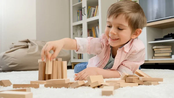 Mały chłopiec budynku domu z zabawek drewnianych bloków na podłodze w salonie. Koncepcja kształcenia dzieci i gier w domu — Zdjęcie stockowe