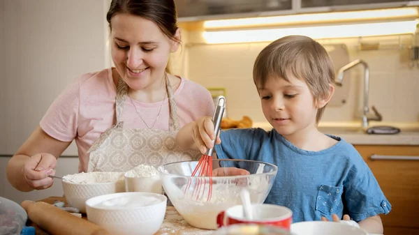 Pasta ya da pasta için hamuru karıştırırken annesine yardım eden tatlı çocuk. Çocuklar aileleriyle yemek pişirir, küçük aşçı olur, aile birlikte vakit geçirir, ev mutfağı olur.. — Stok fotoğraf