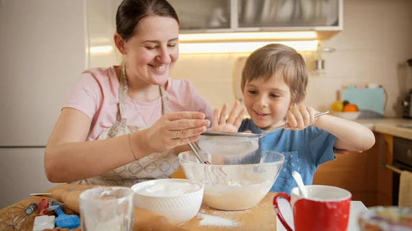 Pasta veya turta hamuru için süzgeçle un karıştıran tatlı bir çocuk. Çocuklar aileleriyle yemek pişirir, küçük aşçı olur, aile birlikte vakit geçirir, ev mutfağı olur.. — Stok fotoğraf