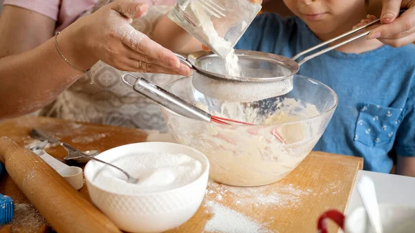 Close-up de menino com a mãe peneirando farinha com peneira. Crianças cozinhar com os pais, pequeno chef, família ter tempo juntos, cozinha doméstica — Fotografia de Stock