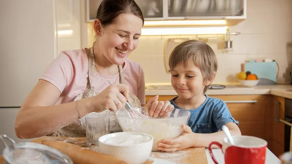 Genç bir anne oğluna bisküvi ya da pasta için hamur karıştırmayı öğretiyor. Çocuklar aileleriyle yemek pişirir, küçük aşçı olur, aile birlikte vakit geçirir, ev mutfağı olur.. — Stok fotoğraf