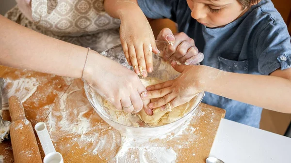 Вид сверху на мать и маленького сына, смешивающих тесто для печенья в стеклянной миске. Дети готовят с родителями, маленький шеф-повар, семья, проводящая время вместе, домашняя кухня. — стоковое фото