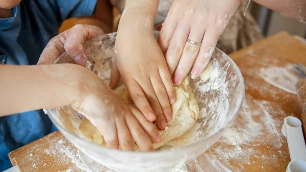 Close-up de mães e crianças mãos amassar ingredientes massa em tigela de vidro ao fazer biscoitos. Crianças cozinhar com os pais, pequeno chef, família ter tempo juntos, cozinha doméstica. — Fotografia de Stock