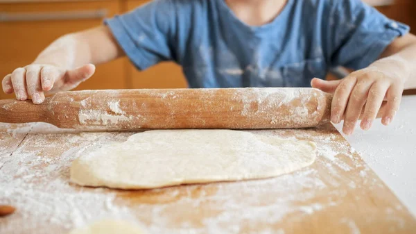 Крупный план маленького мальчика, скатывающегося тесто со скалкой для приготовления пиццы. — стоковое фото