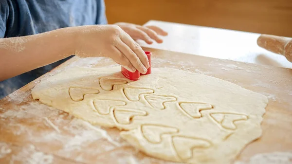 Крупный план маленького мальчика, режущего печенье с пластиковой формой резака. Дети готовят с родителями, маленький шеф-повар, семья, проводящая время вместе, домашняя кухня. — стоковое фото