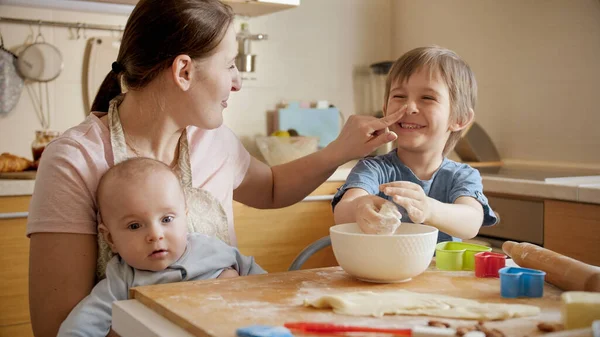Madre felice con i bambini divertirsi e giocare in cucina durante la cottura. Bambini che cucinano con i genitori, piccolo chef, famiglia che ha tempo insieme, cucina domestica — Foto Stock