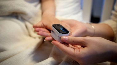 Hastanedeki hasta çocuğun kanında oksijen seviyesini ölçmek için nabız oksimetresi kullanan bir kadın. Coronavirus Covid-19 salgını sırasında çocuk virüsü ve çocukların korunması kavramı.