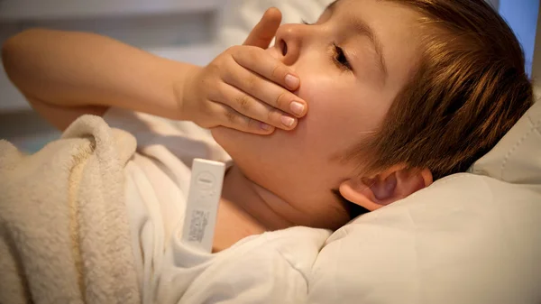 Retrato de menino doente com viru deitado na cama e medindo a temperatura com termômetro digital. Conceito de doença infantil, doença e cuidado dos pais. — Fotografia de Stock