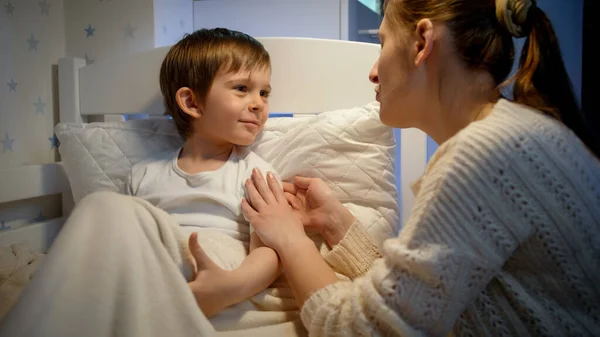 Mały chory chłopiec kaszle w łóżku i rozmawia ze swoją kochającą matką. Koncepcja ochrony dzieci przed wirusami Covid-19 podczas pandemii. — Zdjęcie stockowe