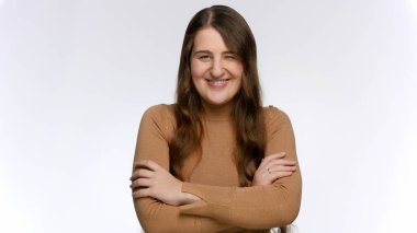 Gülümseyen, göz kırpan ve kameraya gülen genç bir kadının stüdyo portresi.