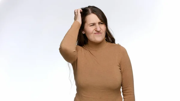 Studio portret van attente jonge vrouw schrobben haar hoofd en denken. Twijfel en frustratie — Stockfoto