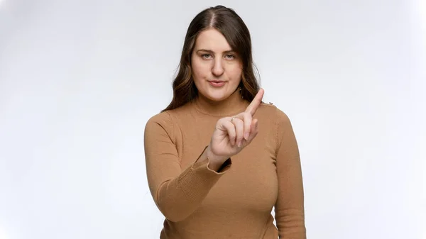 Studioporträtt av en ung kvinna som säger nej och skakar på fingret. Begreppet förbud, förbud och tabu. — Stockfoto