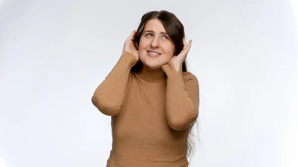 Studio portret van jonge glimlachende vrouw hand in hand naar oren en luisteren naar stemmen om haar heen. — Stockfoto